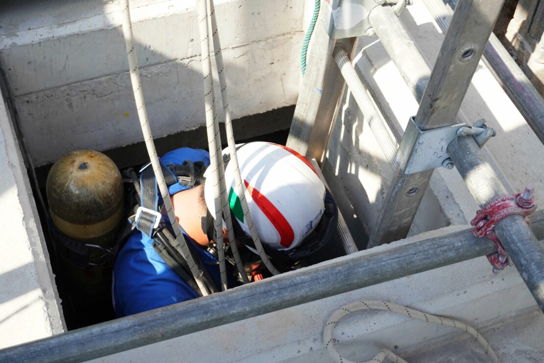 Instructor demonstrating confined space entry procedures to trainees