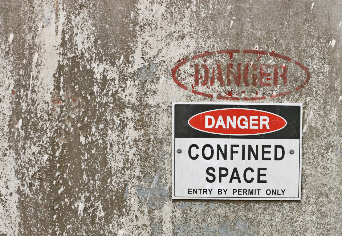 A wall with a sign that says "Danger. Confined Space. Entry by Permit Only."