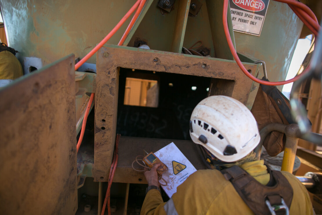 A confined space entry worker holds a manual and gas detection monitor